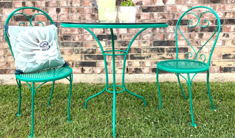 A green metal patio table and two chairs sitting on grass.