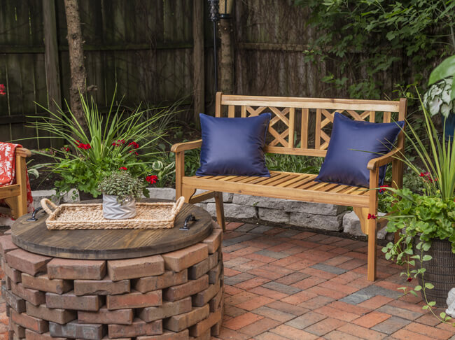 Wood bench with a teak oil finish on brick patio.